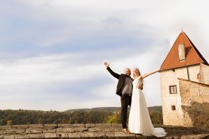 Hochzeitsfotografie stolzes Brautpaar auf Mauervorsprung mit Ausblick