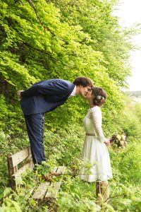 Hochzeitsfotografie küssendes Brautpaar auf einer Waldbank