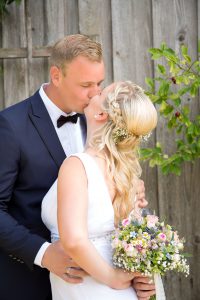Hochzeitsfotografie küssendes Brautpaar vor Holzstadl
